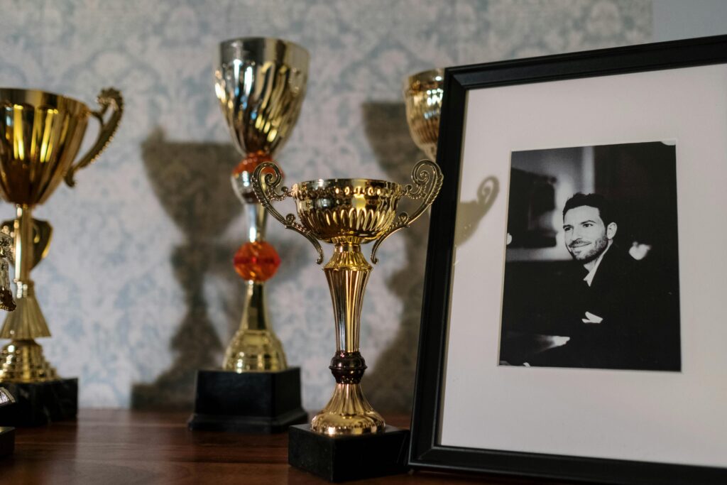 A collection of trophies with a framed black and white portrait on a shelf.